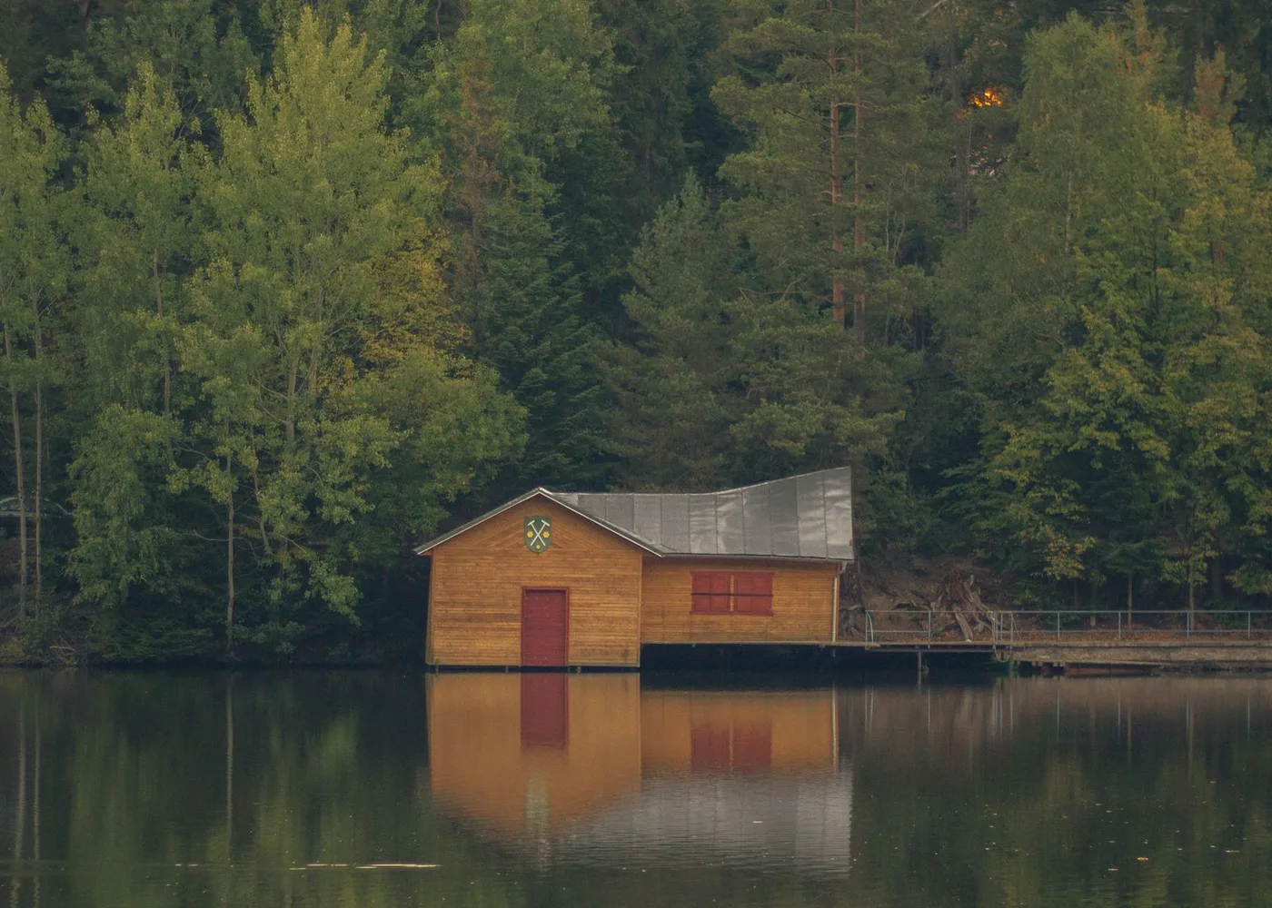 Pieni puinen rakennus tyynen metsäjärven rannalla